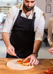 Male chef cooking burger in restaurant kitchen close up - food concept