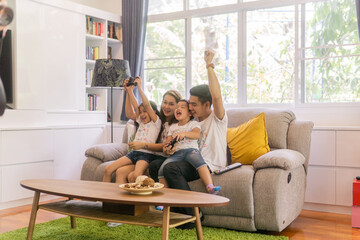 Playful family playing video games together in a living room.