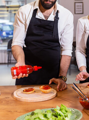 Male chef cooking burger in restaurant kitchen close up - food concept