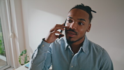 Smiling guy talk smartphone at remote workplace. Man cellphone conversation home