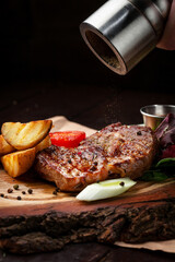 meat steak on a wooden board sprinkled with pepper