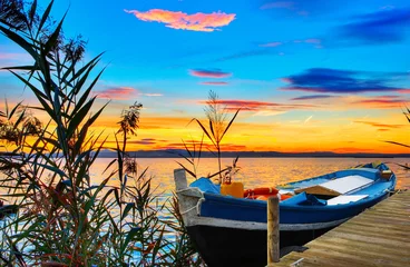 Fototapeten paisaje de un lago con una barca y muchos colores © kesipun