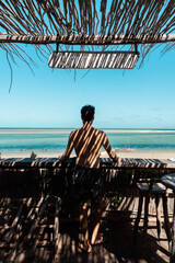 Man on wooden balcony looking out to tropical Beach in vilanculos, Mozambique