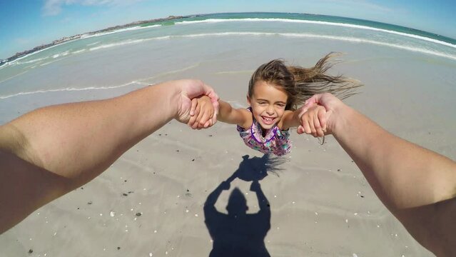 Pov, beach and kid swing with father for summer fun and vacation by the ocean. Game, girl spinning and dad playing with young child by the sea on holiday with happiness and family outdoor by water