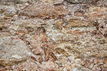 Texture of old stone wall with collapsed plaster. Background of shabby building surface. Destroyed stone wall with fallen plaster. Weathered surface. Copy space. Selective focus