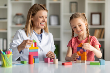 Child Development Specialist Playing Wooden Bricks With Little Girl During Therapy Session
