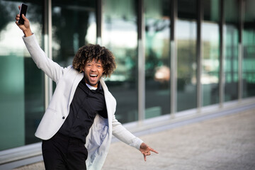 Satisfied black middle aged businessman dancing with happiness near office building outdoors, free...
