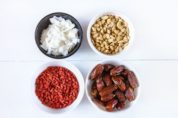 Goji berries, dates, coconut chips and cashews in bowls. Healthy snacks.

