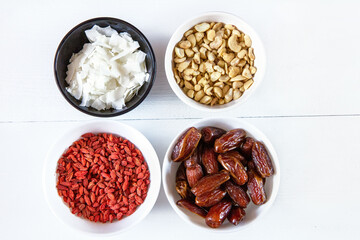 Goji berries, dates, coconut chips and cashews in bowls. Healthy snacks.

