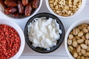 Goji berries, dates, coconut chips, pistachios and cashews in bowls. Healthy snacks.