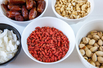 Goji berries, dates, coconut chips, pistachios and cashews in bowls. Healthy snacks.