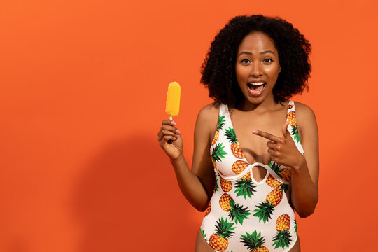 Excited beautiful african american summer lady showing ice pop