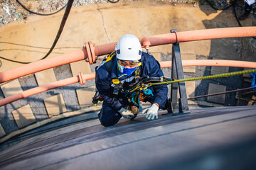 Focus top view male worker down height tank roof rope access safety inspection of thickness storage tank .