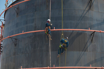 Male two worker rope down access safety inspection of pipe fire water repair storage tank