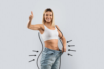 Cheerful slim blonde woman wearing huge jeans, showing thumb up