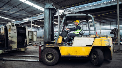 Fototapeta na wymiar Industrial worker driving a forklift in the factory. Engineer is working and maintaining in the warehouse.