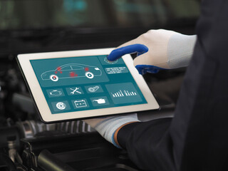 Technicians use tablet computers with futuristic interactive diagnostic software. An expert inspects the vehicle to look for damaged parts in the engine compartment.