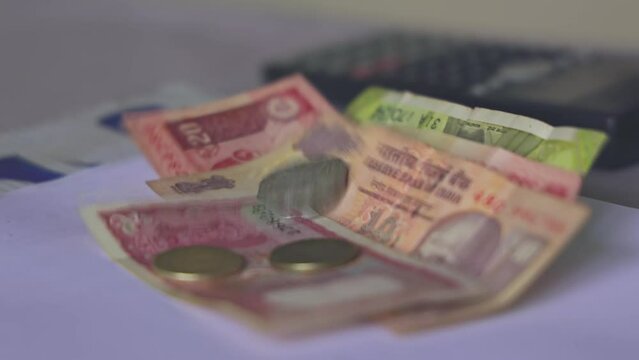 Closeup of Indian rupee coins falling over currency notes on a table