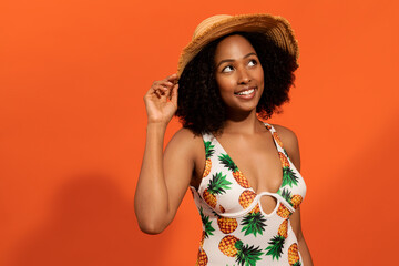 Cute relaxed black woman wearing swimsuit and straw hat