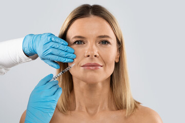 Beautiful middle aged woman getting cosmetic injection in nasolabial folds