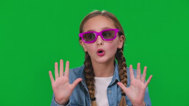 Closeup charming girl putting on 3D glasses moving hands with excited facial expression. Close-up portrait of Caucasian teenager enjoying watching film on green screen background