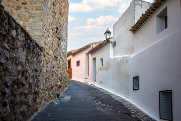 Fototapeta na wymiar Narrow steep street in the old town of Moratalla, Murcia, Spain, with whitewashed houses and medieval wall