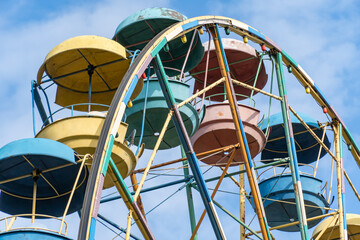 Old colorful ferris wheel in amusement park. Multicolour soviet carousel on blue sky background. Entertainment tall circle rotate in city. Round attractions of holiday for family. Traditional leisure.