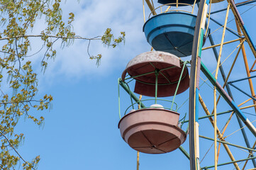 Old colorful ferris wheel in amusement park. Multicolour soviet carousel on blue sky background....