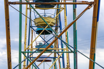 Old colorful ferris wheel in amusement park. Multicolour soviet carousel on blue sky background. Entertainment tall circle rotate in city. Round attractions of holiday for family. Traditional leisure.