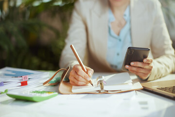 Modern business woman in green office using phone