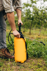 A farmer is using herbicides to get rid of weed in his garden.