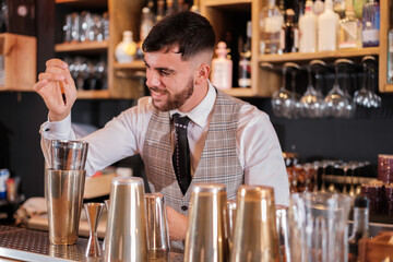 Young bartender preparing a cocktail in a bar. Concept: preparation, drink, offer