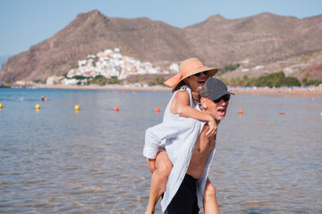Senior couple climbing on top of each other having a fun time at the beach. Concept: pensioner,...