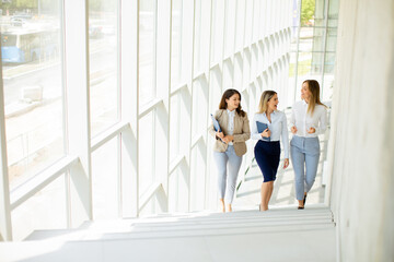 Three young business women walking on stairs in the office hallway