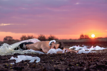young man with athletic figure wrapped in plastic on the ground