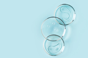 Cosmetic beauty concept with bottle serum, drops and petri dish on blue background