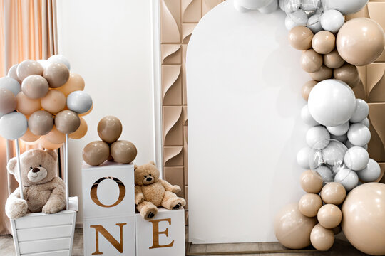 Arch decorated with golden, white balloons and soft teddy bears for birthday party. Celebration concept. Trendy decor. Copy space, place for text. Children's photo zone for girl 1 year and photo wall