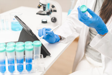 Fototapeta na wymiar Medical development research laboratory, chemist or science woman scientist student hand holding pipette for test analysis liquid samples, using tablet in lab. Microbiology, analysing for medicine.