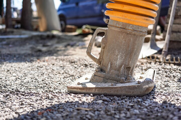 Gravel compactor or portable vibratory tamper on construction site, detail to machine lower part