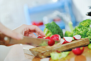 woman preparing healthy food salad with green and red vegetable and knife