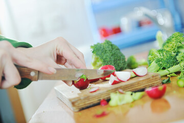 woman preparing healthy food salad with green and red vegetable and knife