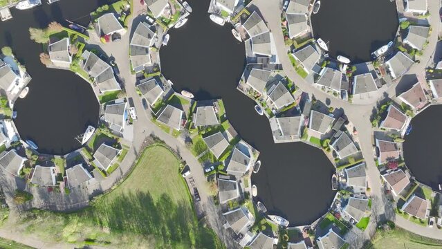 Aerial drone video of a housing compound along a lake. Shaped semi circle with private parking and boat dock in a town called Lemmer, the Netherlands.