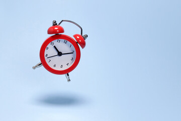 flying levitating red alarm clock on a blue background close-up