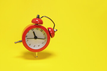 Flying red alarm clock on yellow background. copy space for text