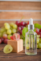 Serum grape seed oil with dropper pipette on grapes background podium close-up. Beauty skincare and healthcare concept.
