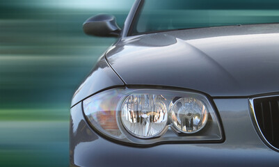Front of a car with a blurred background. Metallic paint texture on car, not noise. Focus on lights.