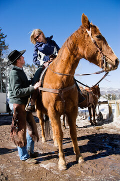Wrangler talking to woman on horse.