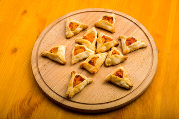 Triangular gomentashi cookies for the Purim holiday on a chalkboard are laid out on a chalkboard on a light table.