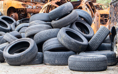 Garbage from a pile of black old car tires. Environmental pollution. Ecological problems. Old car tires thrown into an industrial landfill for recycling. Reuse of worn rubber tires.