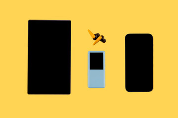 Phone, mp3, headphones and tablet on yellow background.  Listen audiobook online concept, online...
